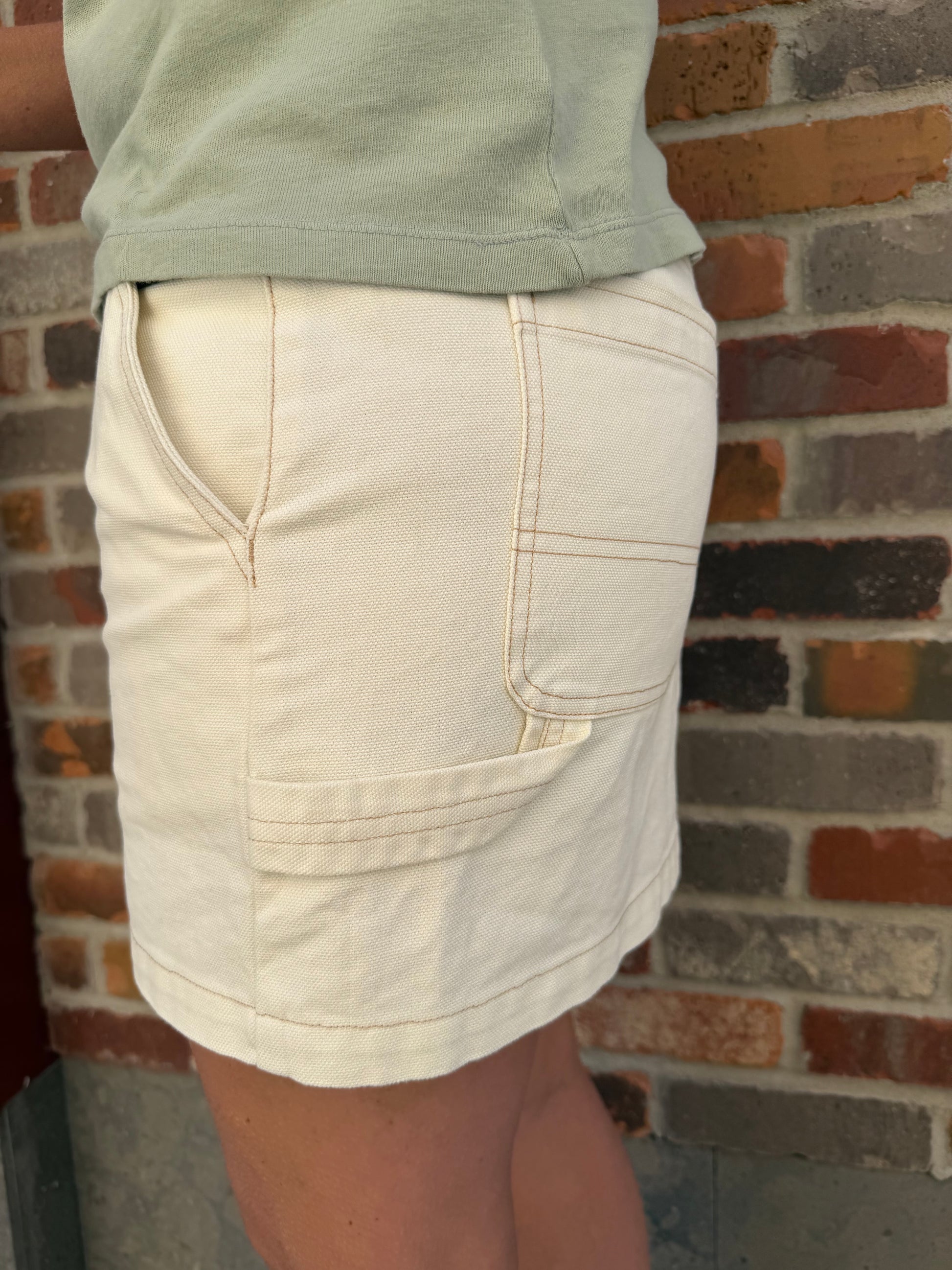 Close-up of light-colored shorts against a brick wall.