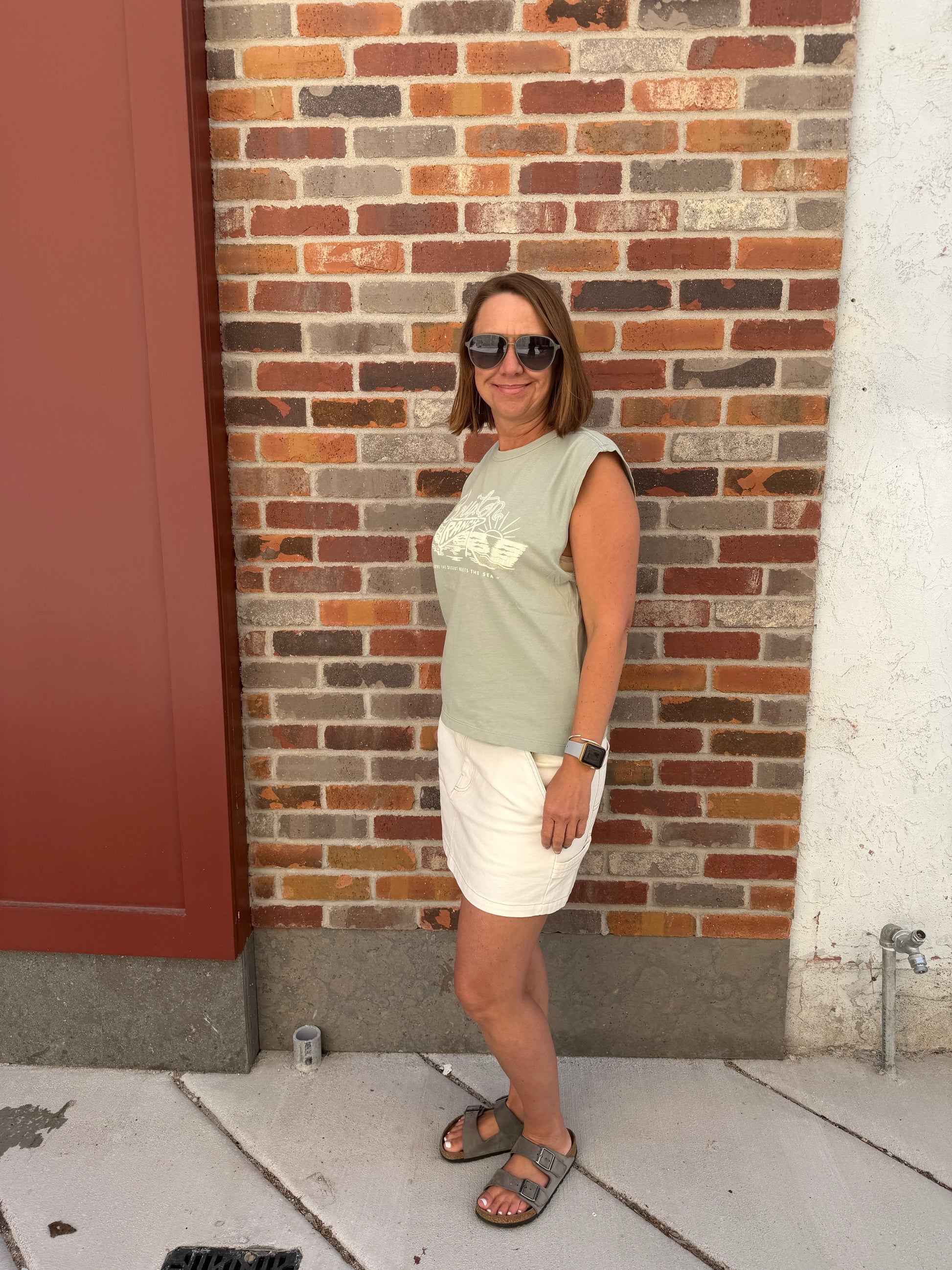 Person standing on a sidewalk with a brick wall in the background