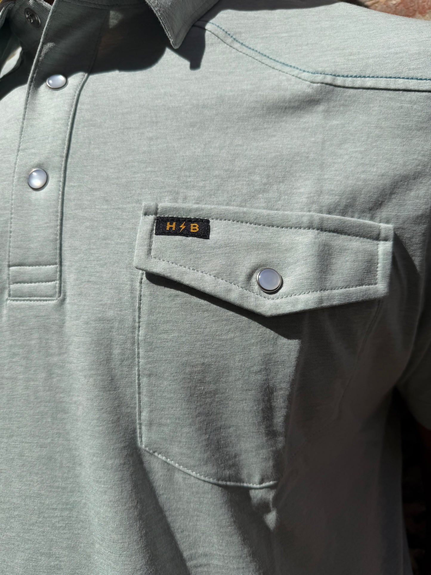 Close-up of a gray jacket with a button and brand label.