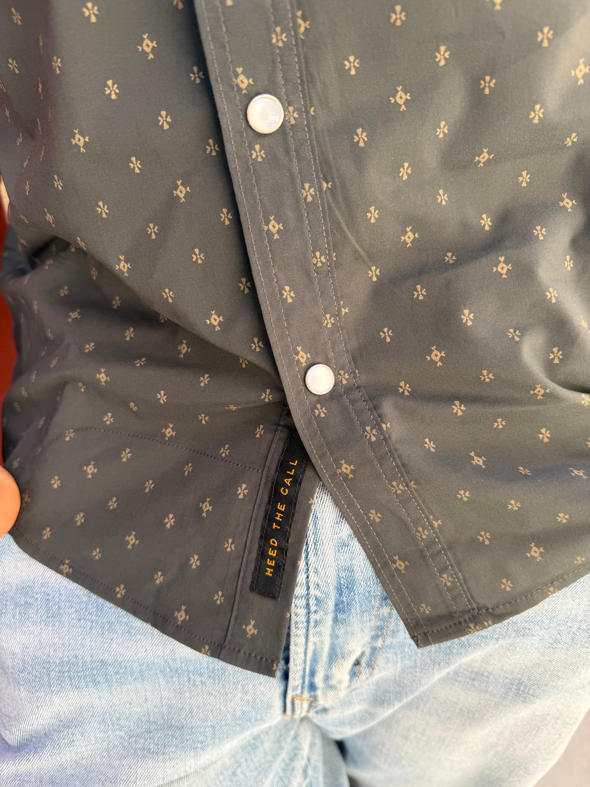 Close-up of a dark gray jacket with gold floral patterns and a visible brand label.