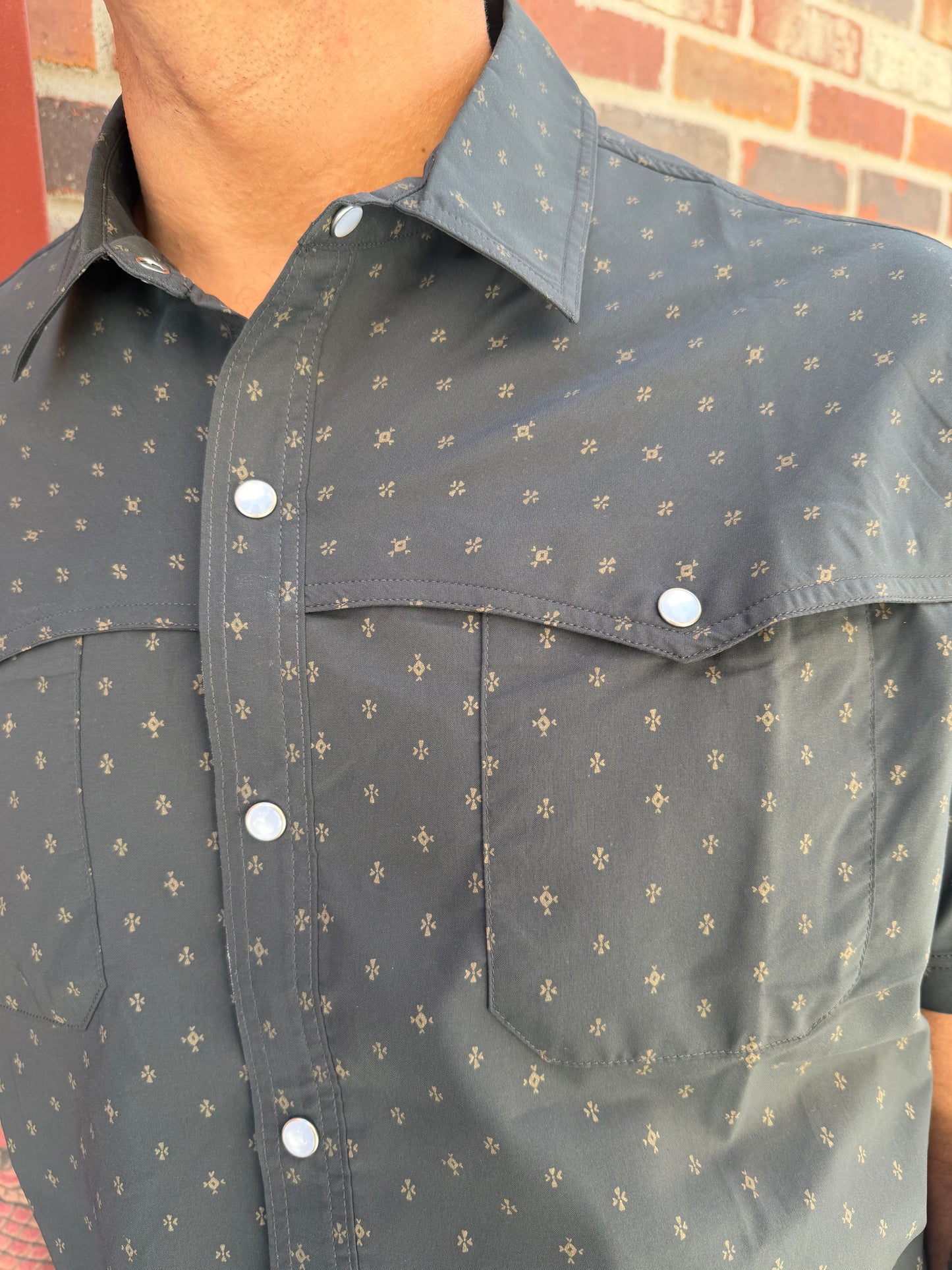 Gray shirt with white button details on a brick surface