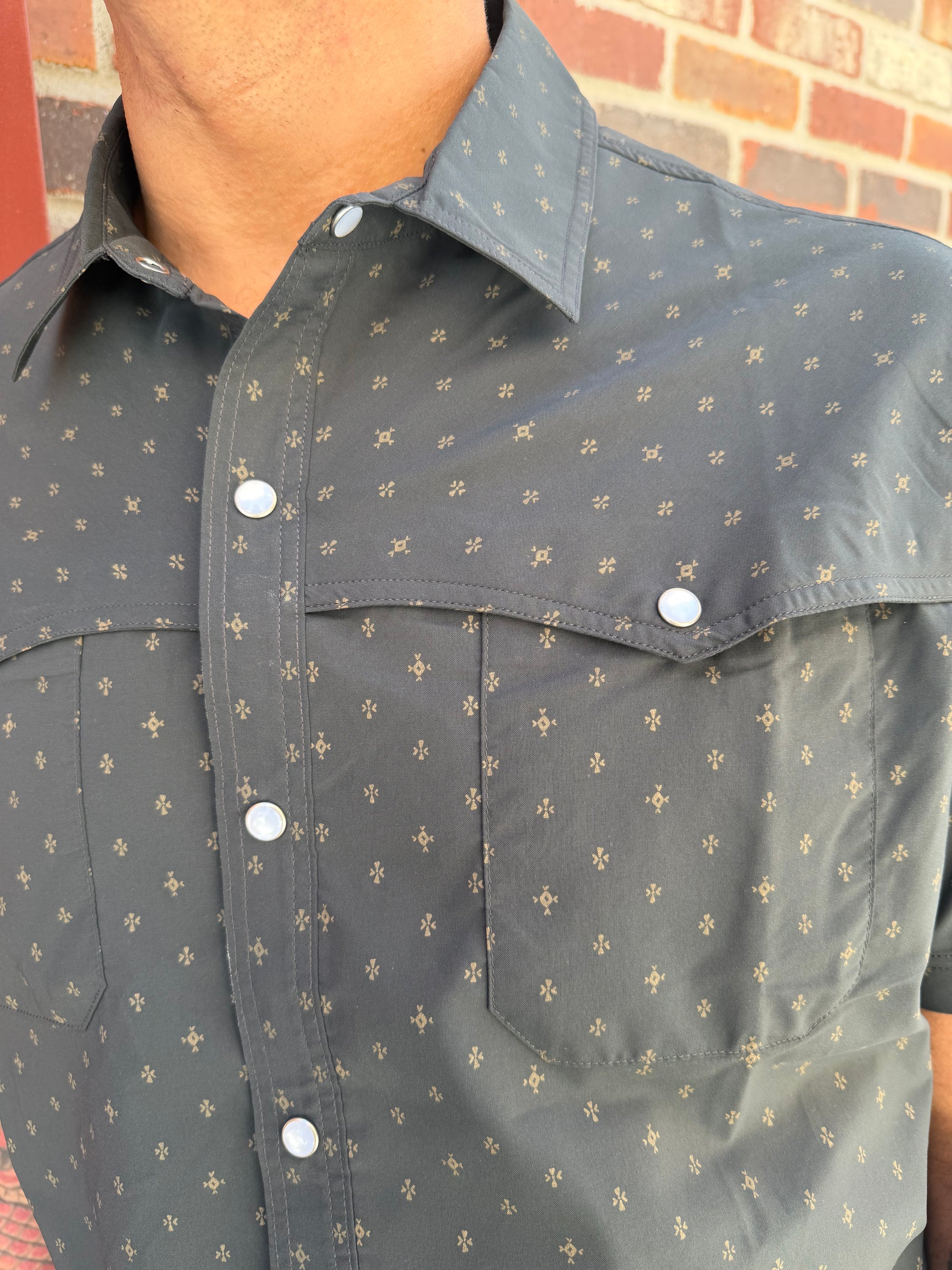 Gray shirt with white button details on a brick surface