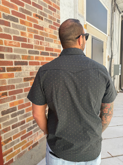 Person wearing a dark shirt with small patterns on a brick pavement.