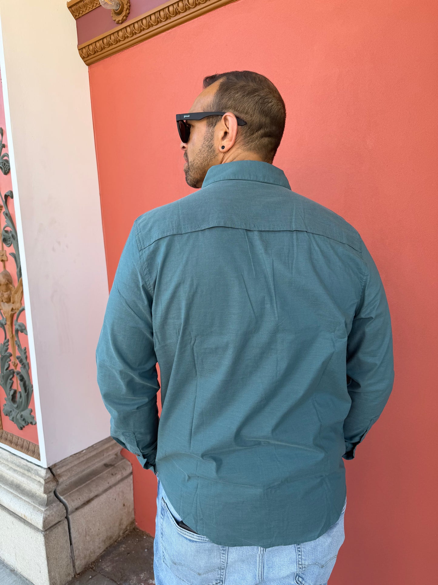 Person wearing a blue jacket in an indoor setting with a pinkish wall.
