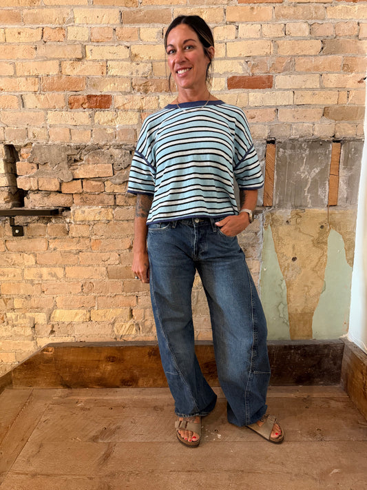Person standing in a room with a textured brick wall and wooden floor.