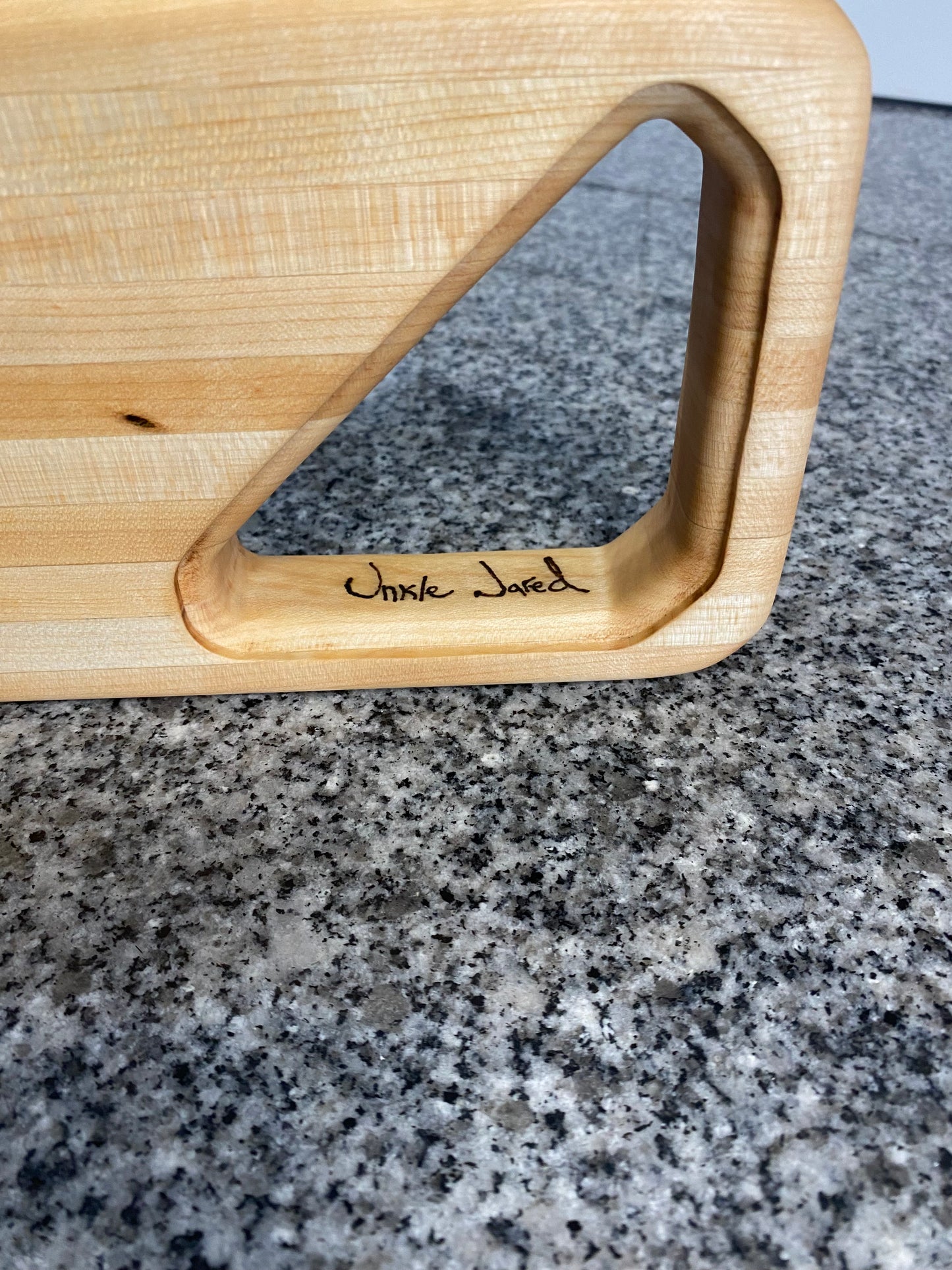 Wooden cutting board with a handle on a granite countertop