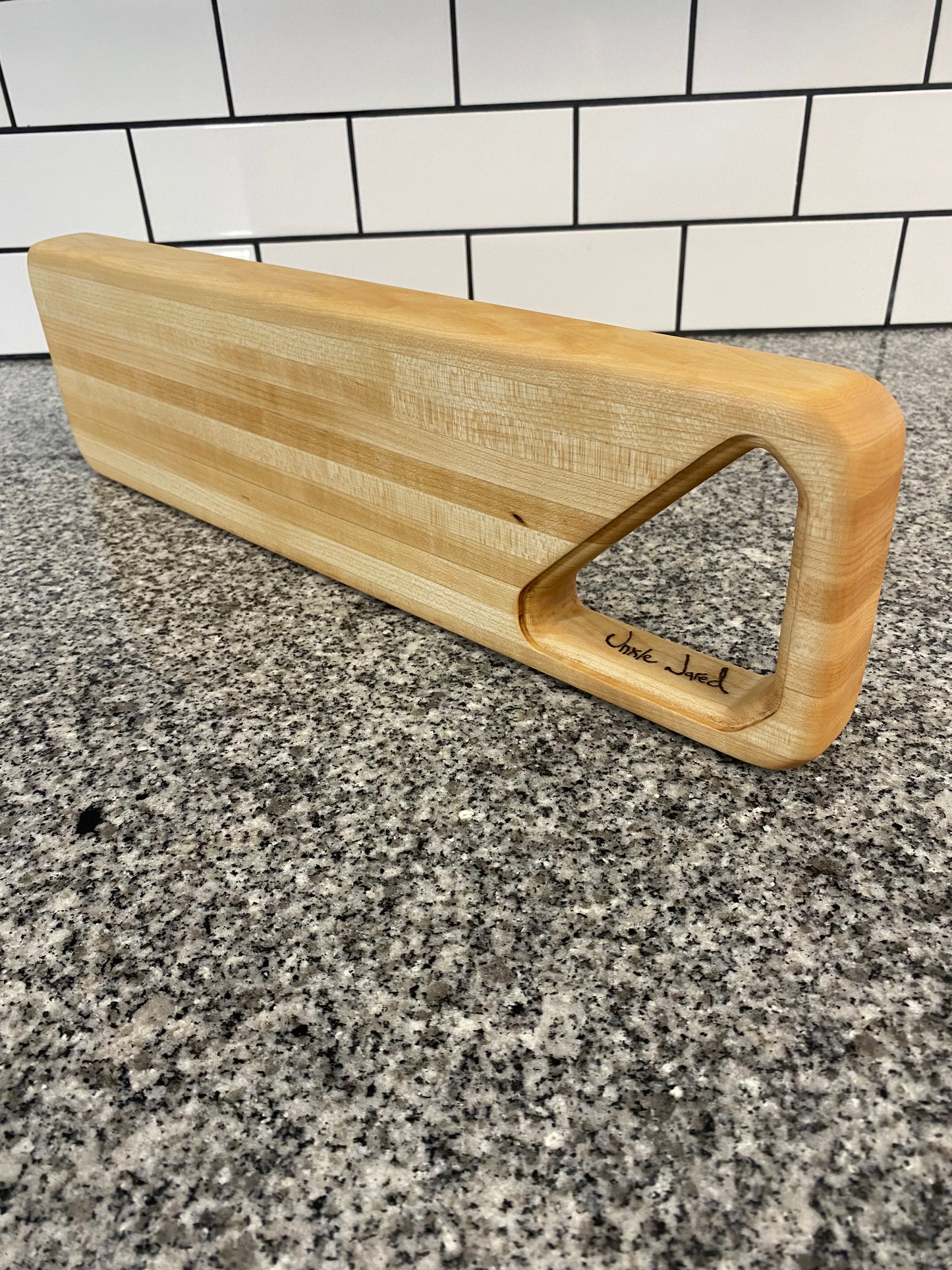 Wooden cutting board on a textured surface with tiled background