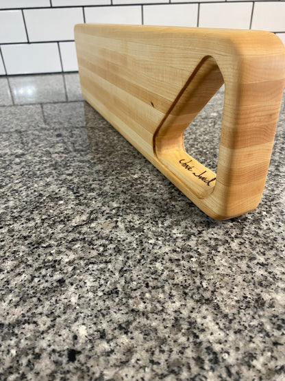 Wooden cutting board with 'Unkle Jared" branding on a granite countertop.