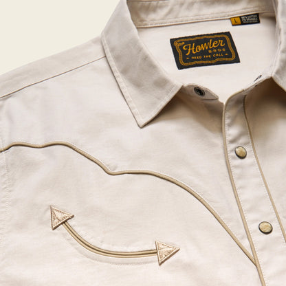 Close-up of a beige jacket with an embroidered arrow design and 'Howler Bros' label.