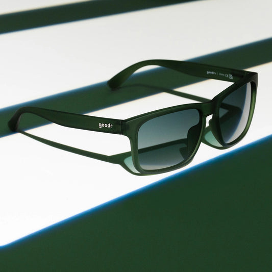 Green sunglasses with 'goodr' branding on a reflective surface
