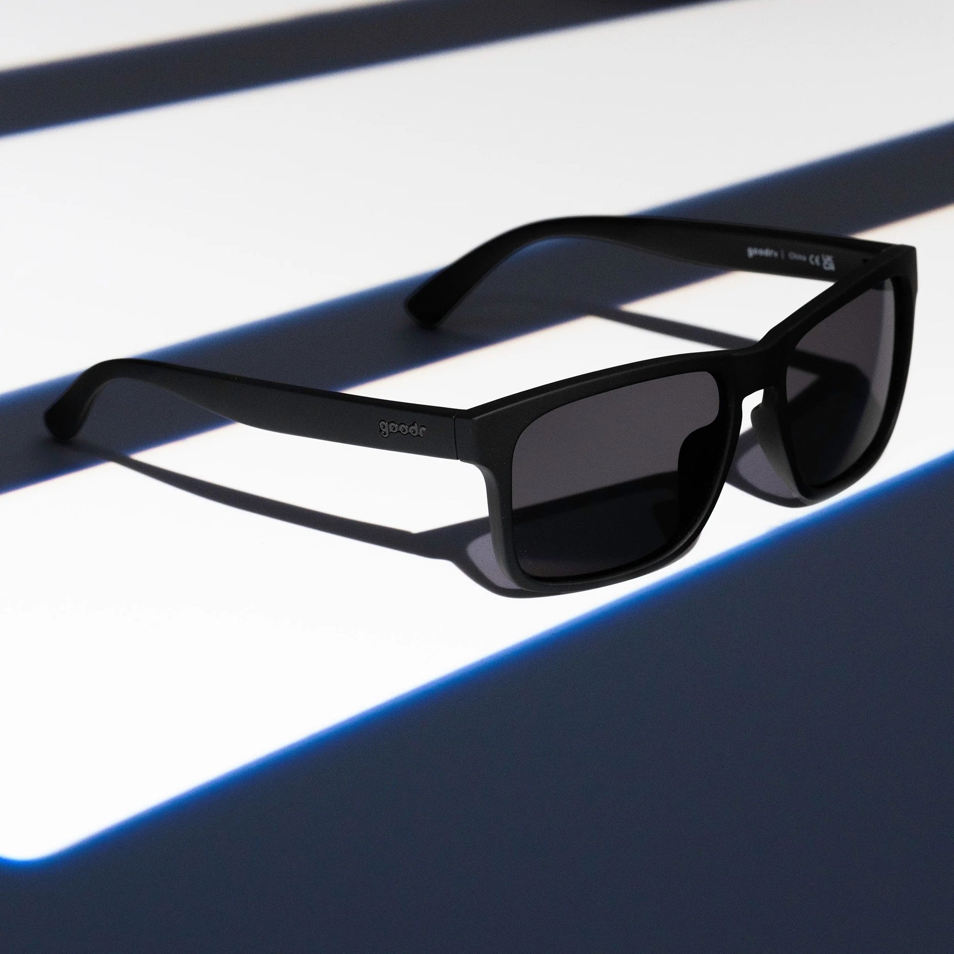 Black sunglasses with dark lenses on a reflective surface