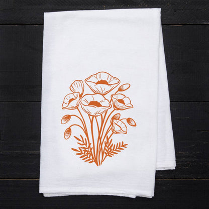 White towel with orange floral design on a black wooden surface