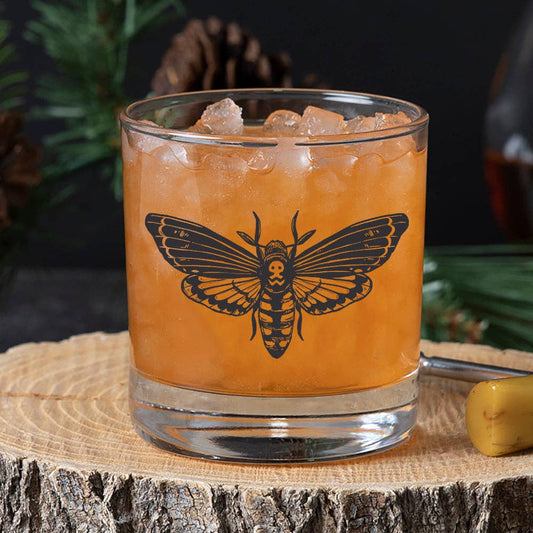 Orange cocktail with ice and moth design in a glass on a wooden surface