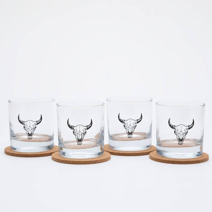 Four glass tumblers with bull skull designs on cork coasters against a white background
