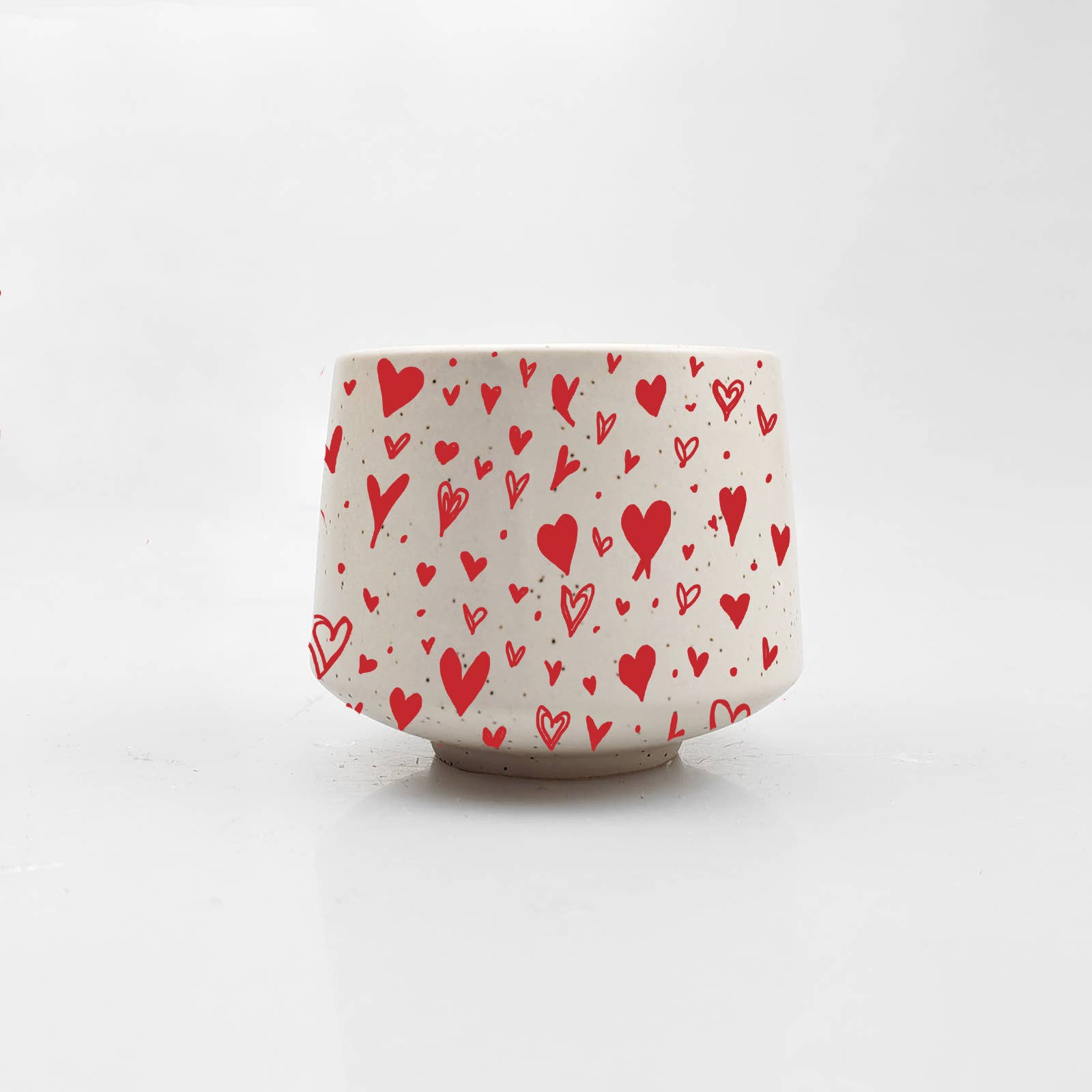 Ceramic cup with red heart pattern on a white background