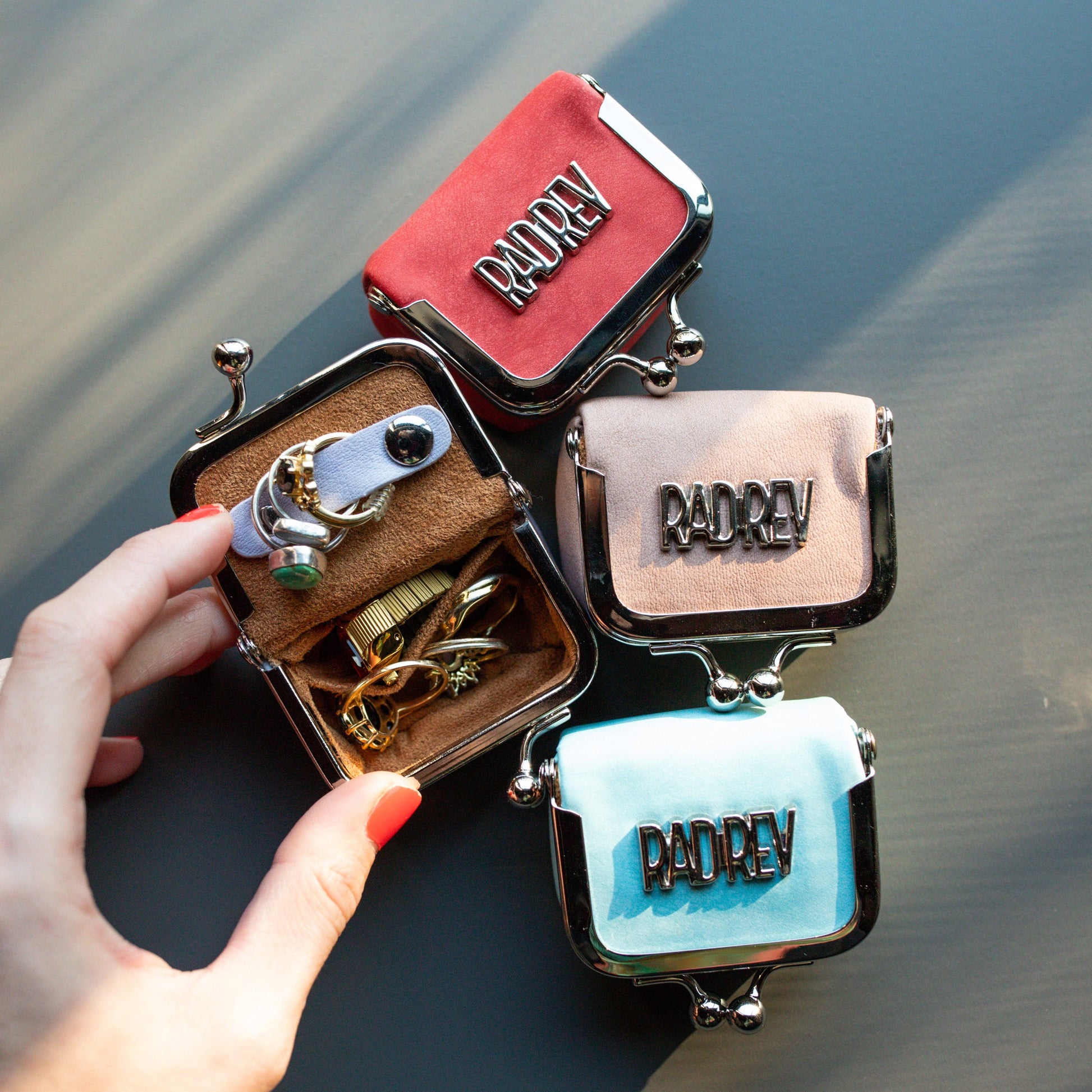 Set of small, colorful bags with 'RADREY' branding held by a hand.