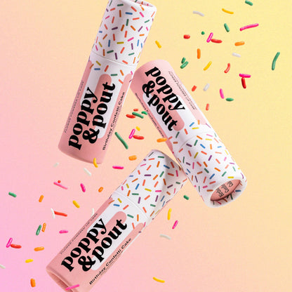 Three 'Poppy & Pout' lip balm tubes with colorful sprinkles on a gradient background