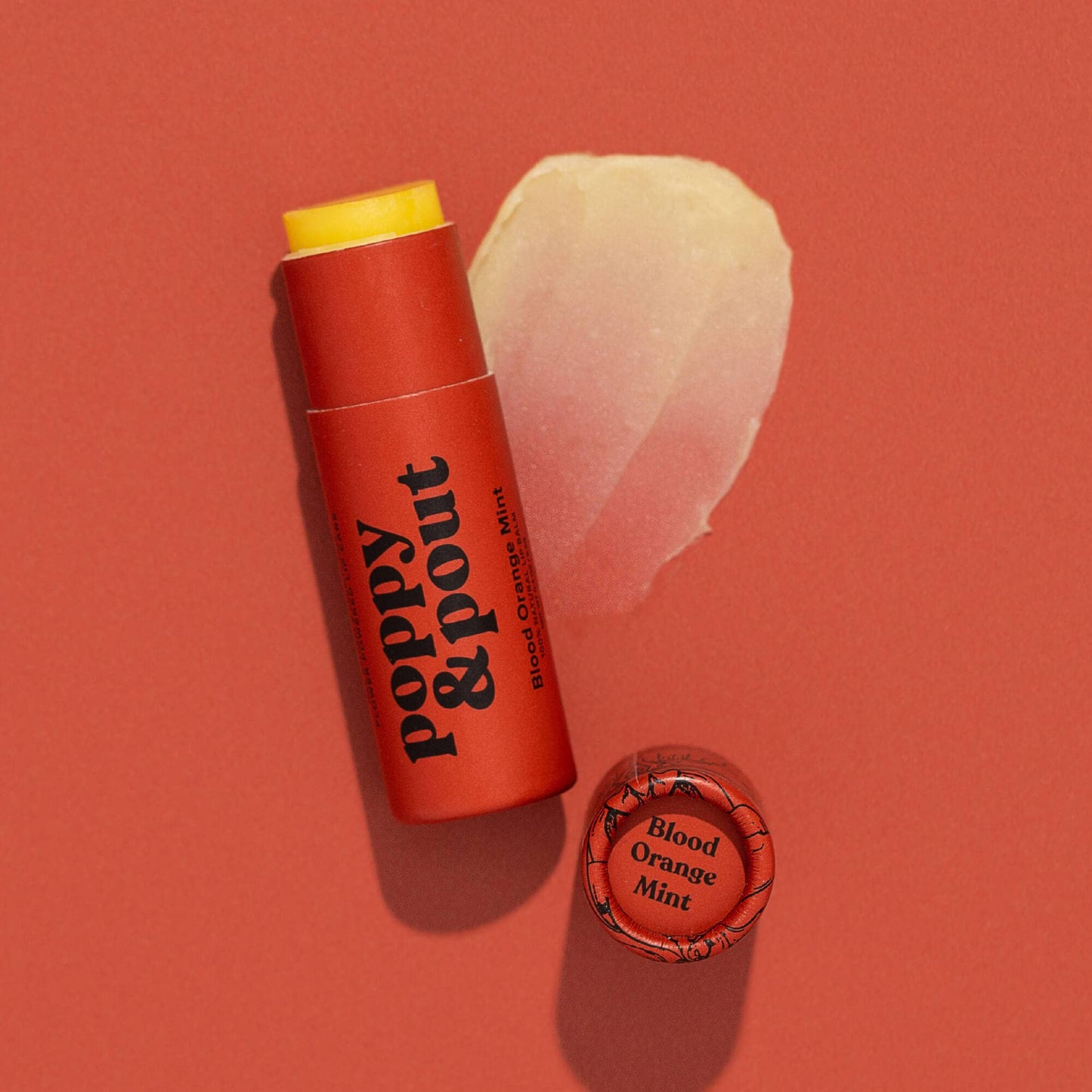 Lip balm stick with 'Poppy & Pout' branding on a red background