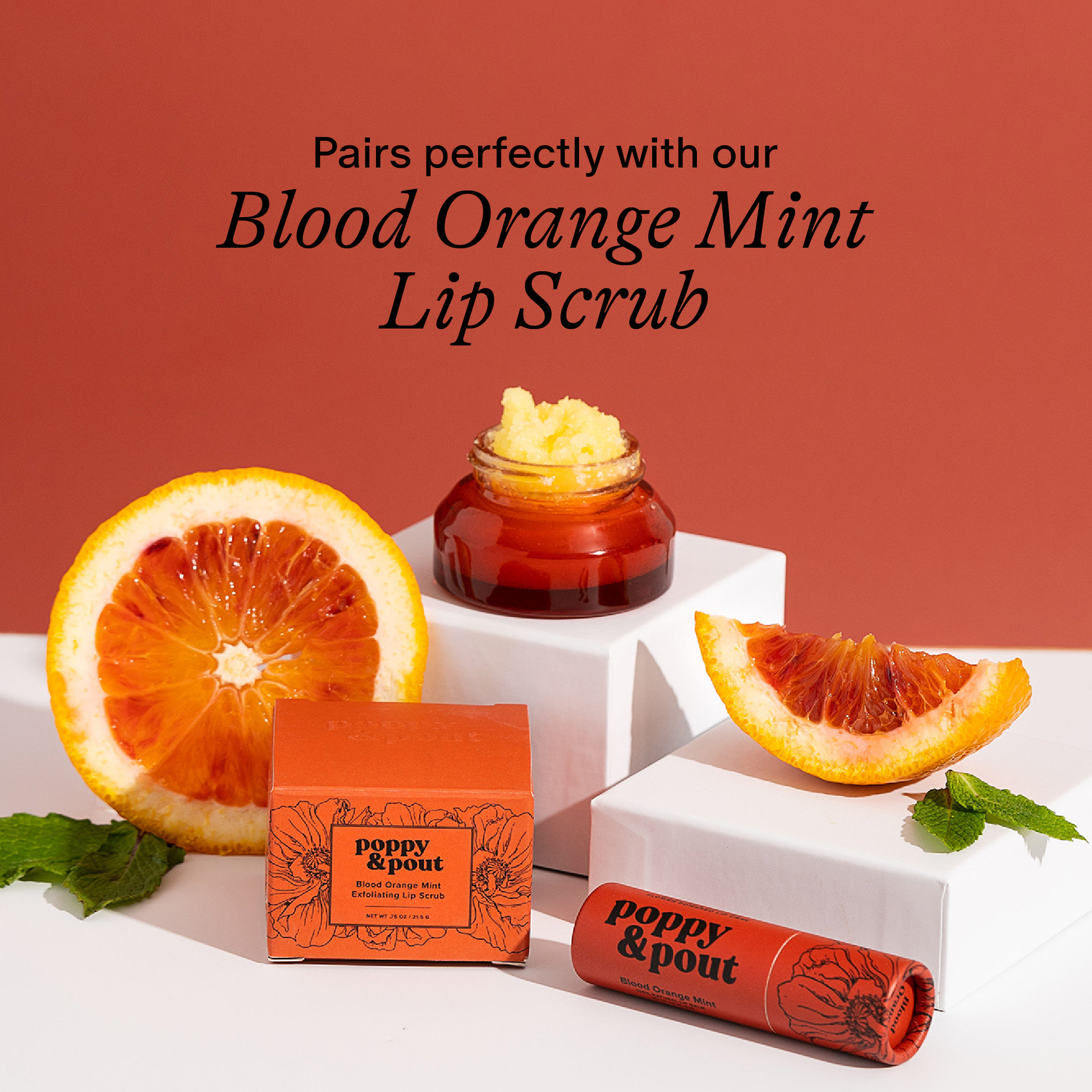 Blood Orange Mint Lip Scrub with orange slices and mint leaves on a red background