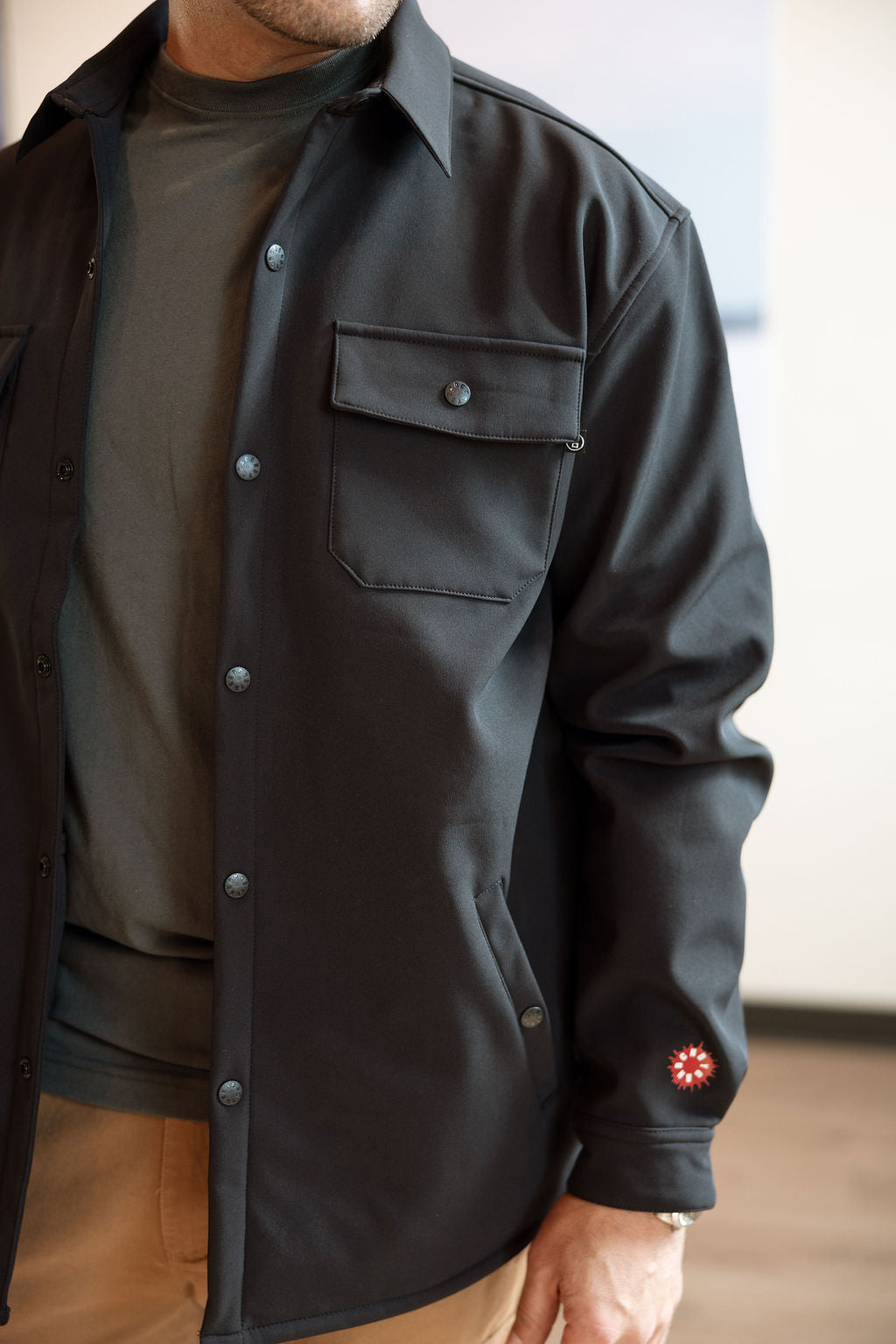 Person wearing a dark jacket with a visible brand logo indoors