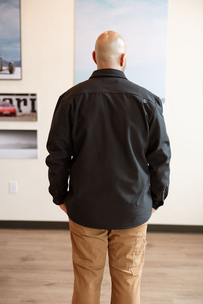 Person wearing a black jacket and tan pants standing in an art gallery.