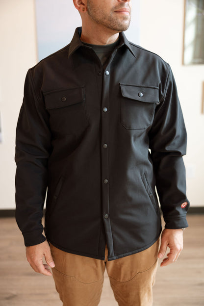 Man wearing a black button-up shirt with a neutral background