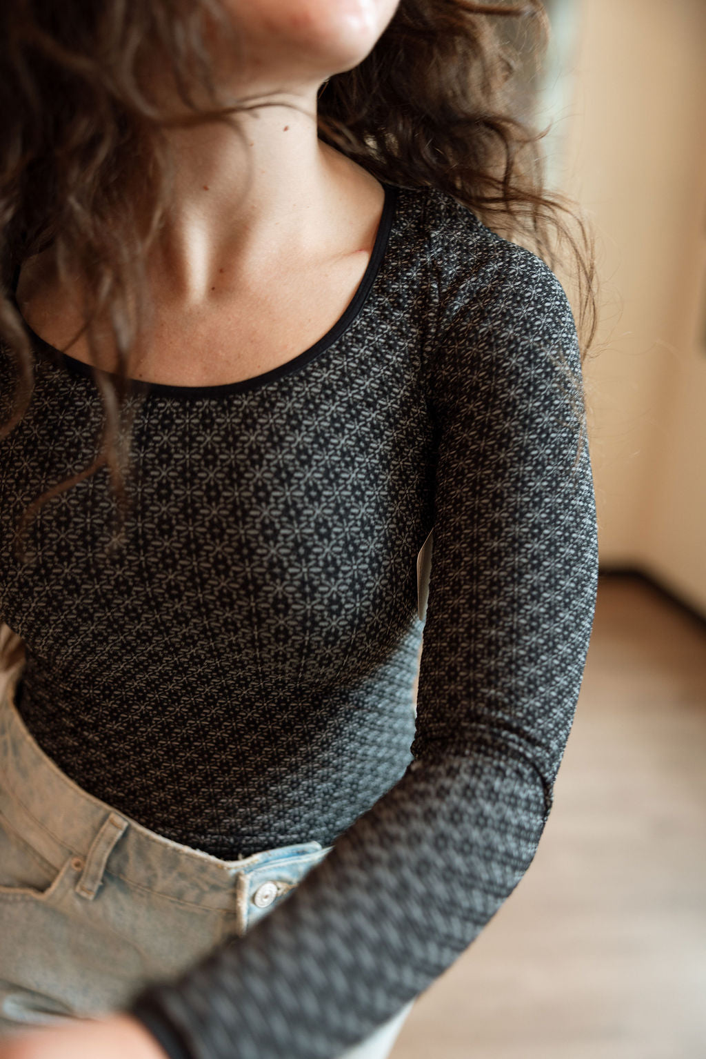 Person wearing a textured black long-sleeve top with a blurred background